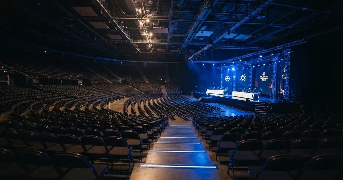 Pusta arena z półkolem siedzisk i oświetloną niebieskim światłem sceną, widok z góry na rzędy foteli.